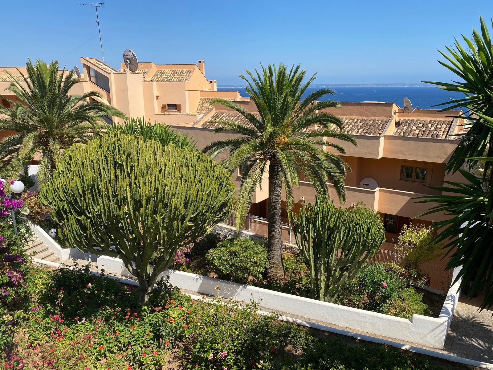 Residencia de estilo mediterráneo color ocre con jardines de cactus y palmeras frente al mar azul.