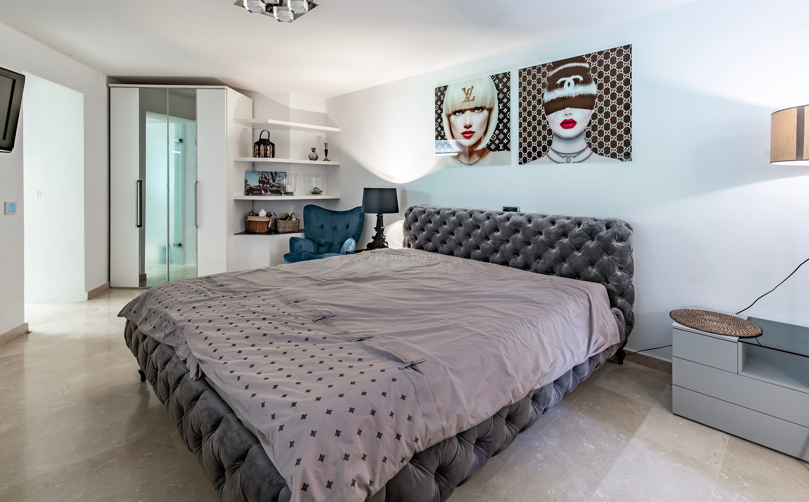 Chambre principale avec lit capitonné gris, sol en marbre poli et placards intégrés au design contemporain.