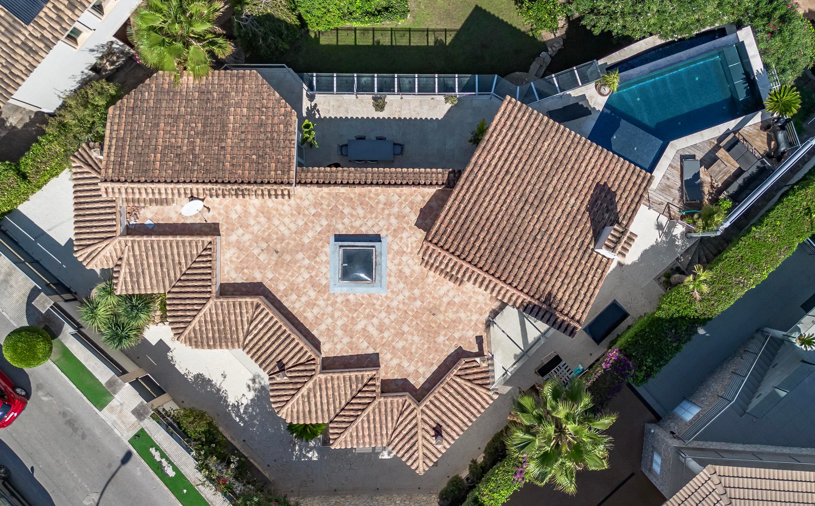 Vue aérienne par drone d'une villa de luxe avec toits en tuiles, piscine privée et jardins paysagers.