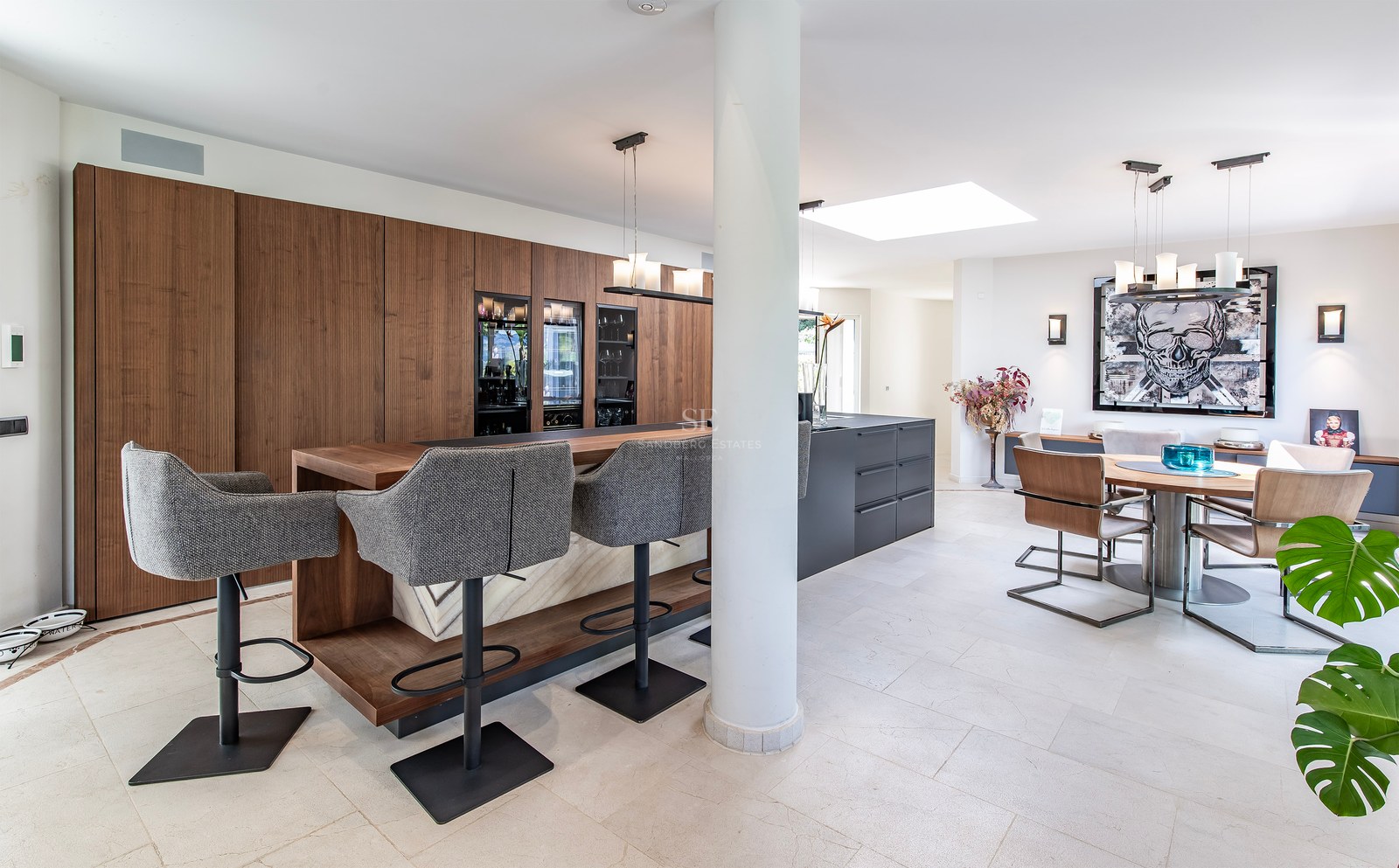 Cuisine moderne ouverte avec bar en bois, îlot gris, caves à vin et espace salle à manger contemporain.