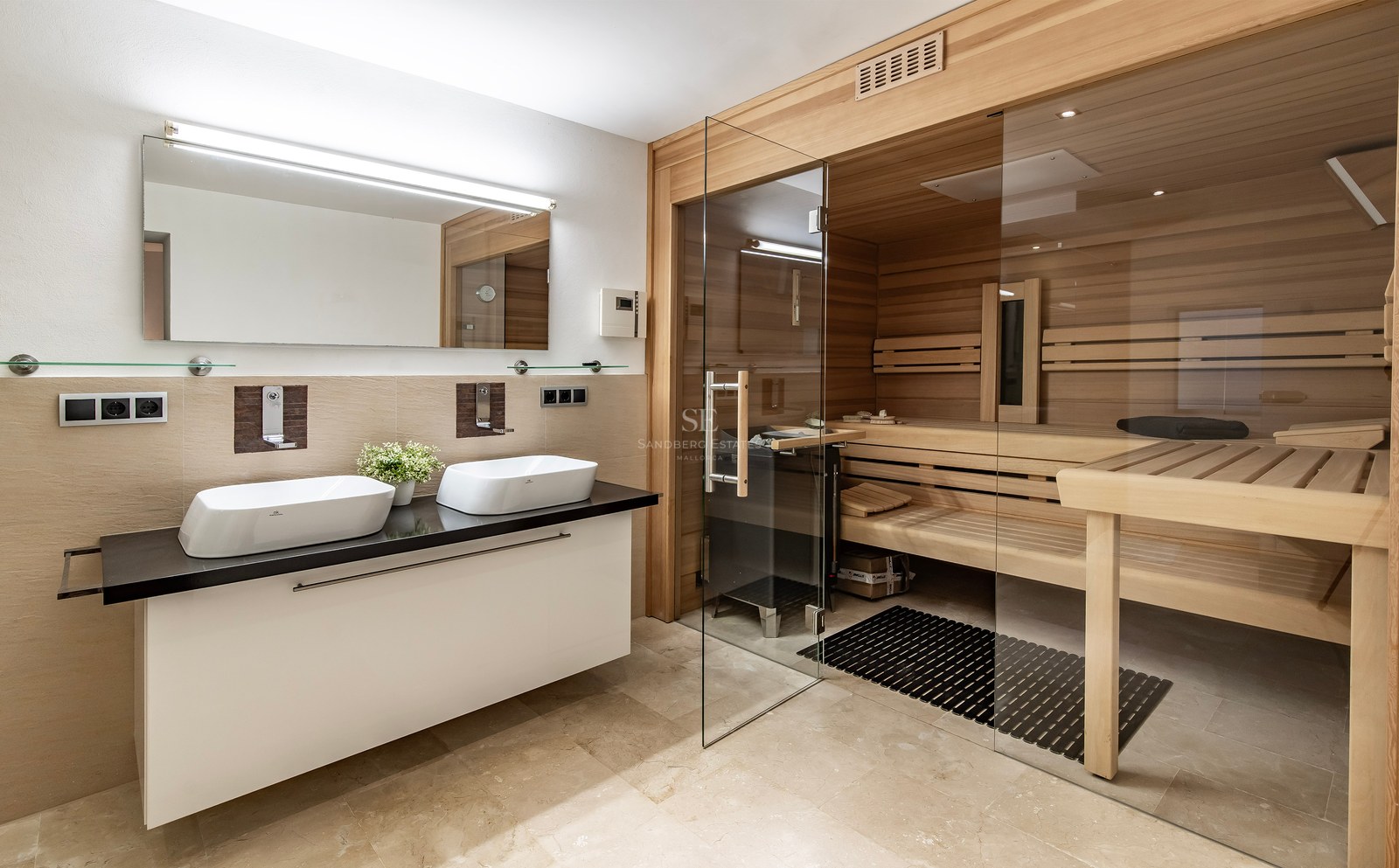 Salle de bain luxueuse avec sauna en bois intégré, porte vitrée et double vasque sur plan de travail noir.