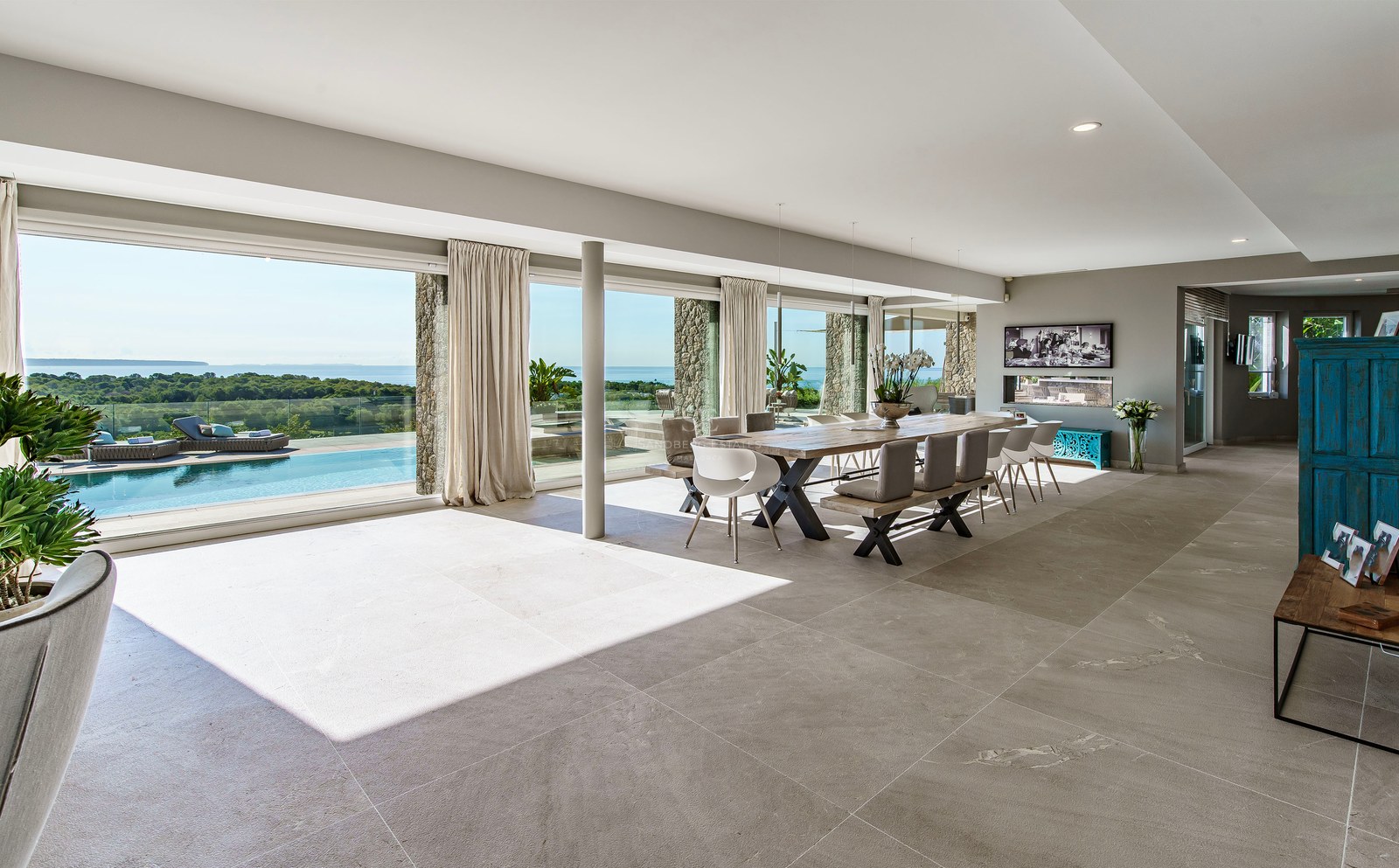 Comedor espacioso con ventanales de suelo a techo frente a una piscina infinita y vistas al Mediterráneo.