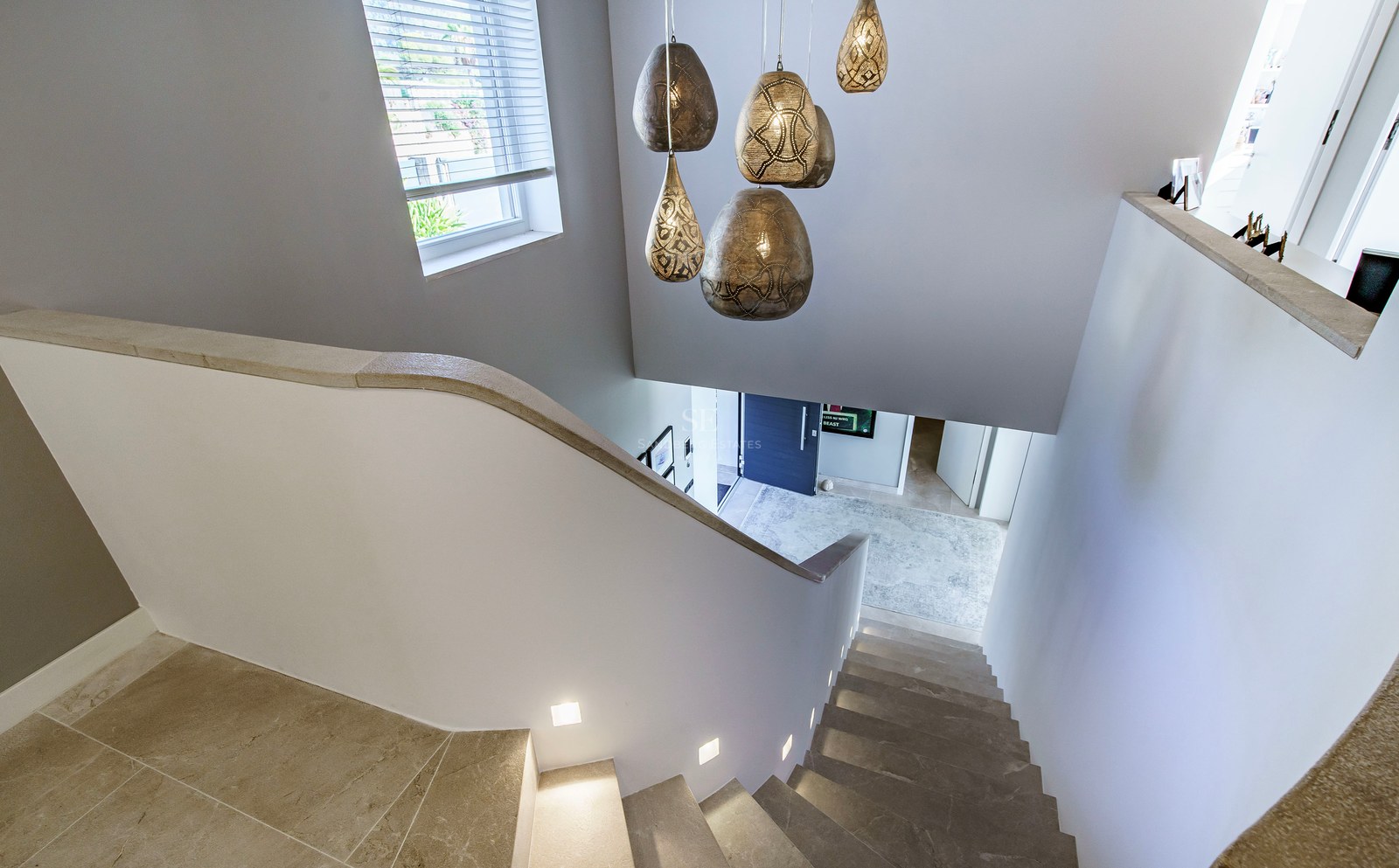 Escalera de piedra con luces LED integradas y lámparas de diseño vista desde arriba hacia la entrada.