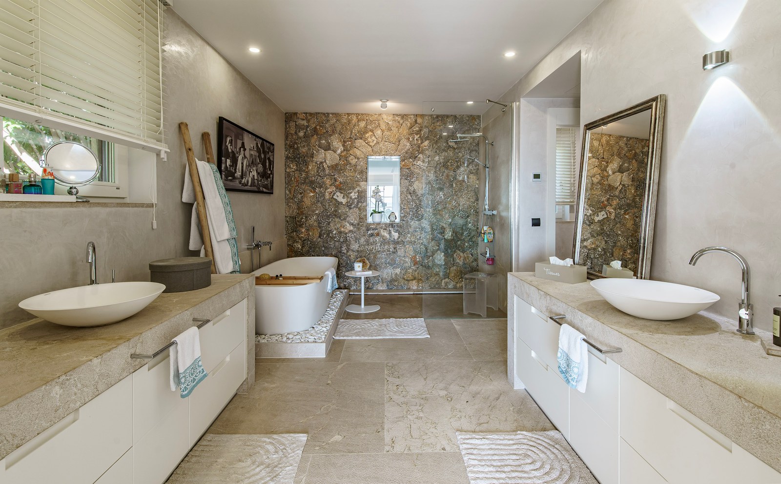 Baño principal contemporáneo con bañera exenta, pared de piedra natural, ducha italiana y lavabo doble.