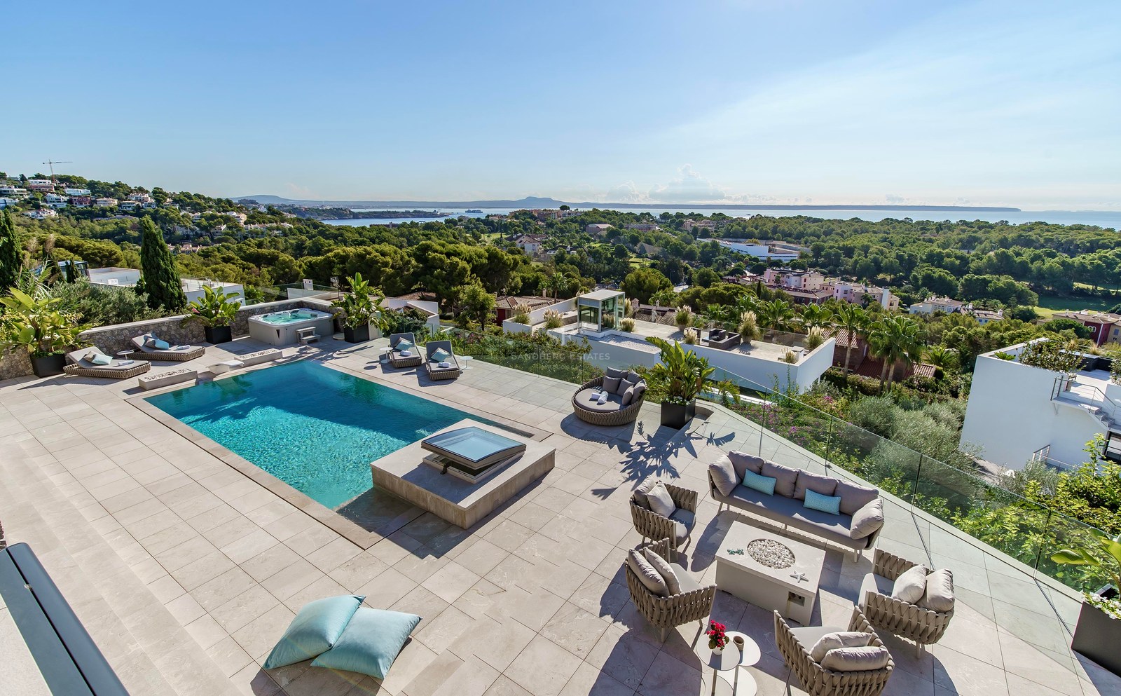 Terraza elevada con piscina turquesa, mobiliario de salón exterior y barandillas de cristal con vistas al Mediterráneo.