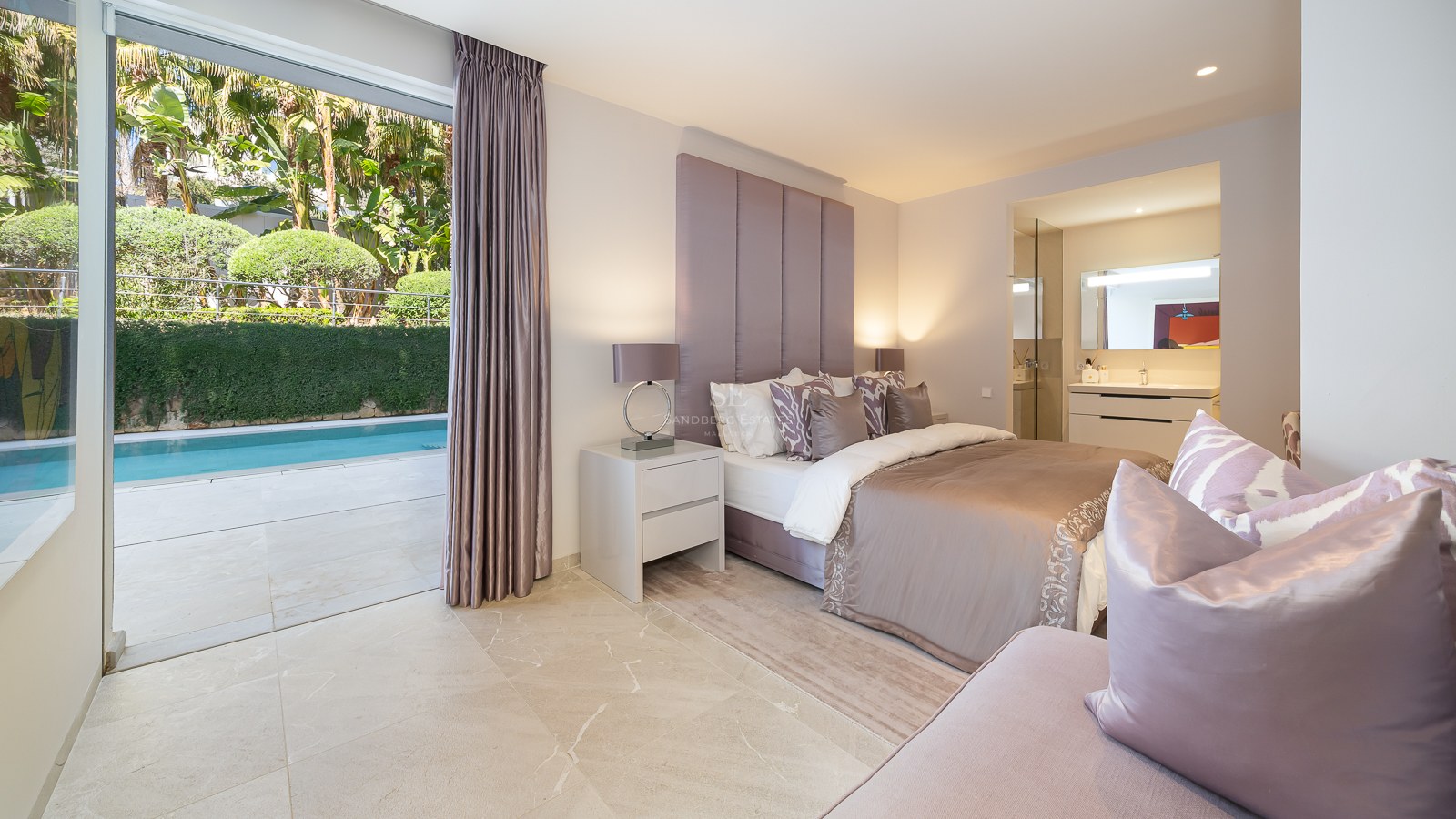 Modern bedroom with marble floors and large glass doors opening directly onto a private terrace and swimming pool.