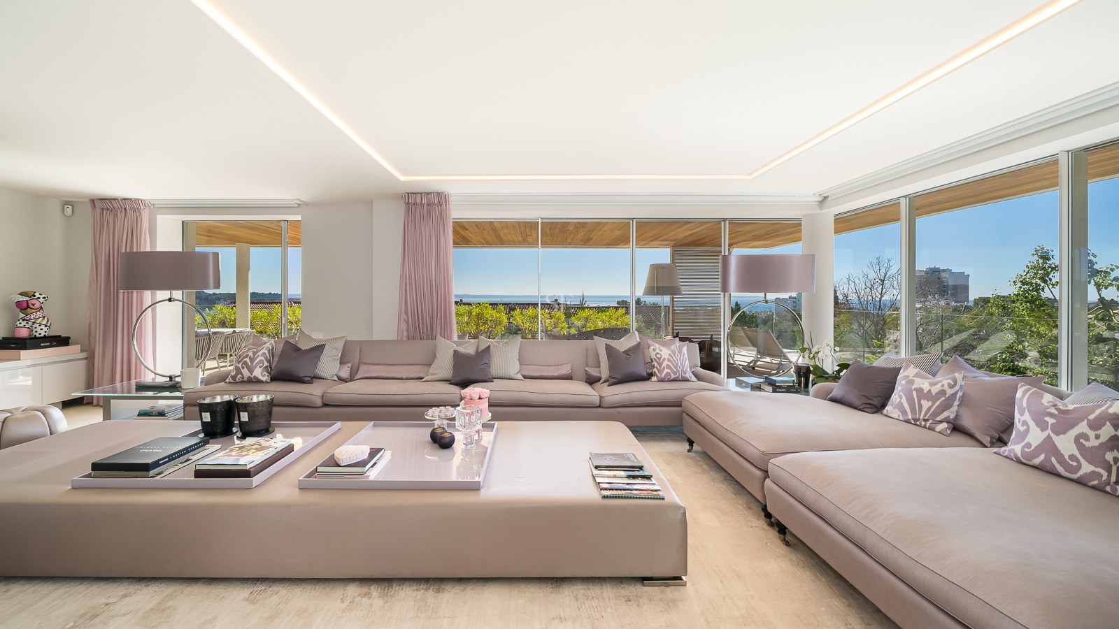 Large mauve modular sofa in a bright living room with floor-to-ceiling windows overlooking the Mediterranean sea.