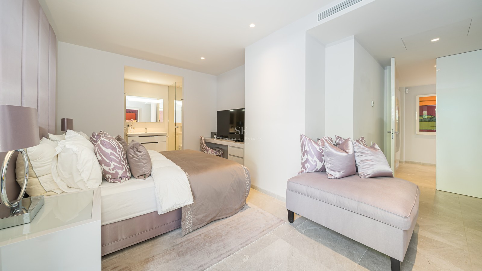 Bright master bedroom with marble floors, plush bed with lavender accents, and a view into a modern en-suite bathroom.