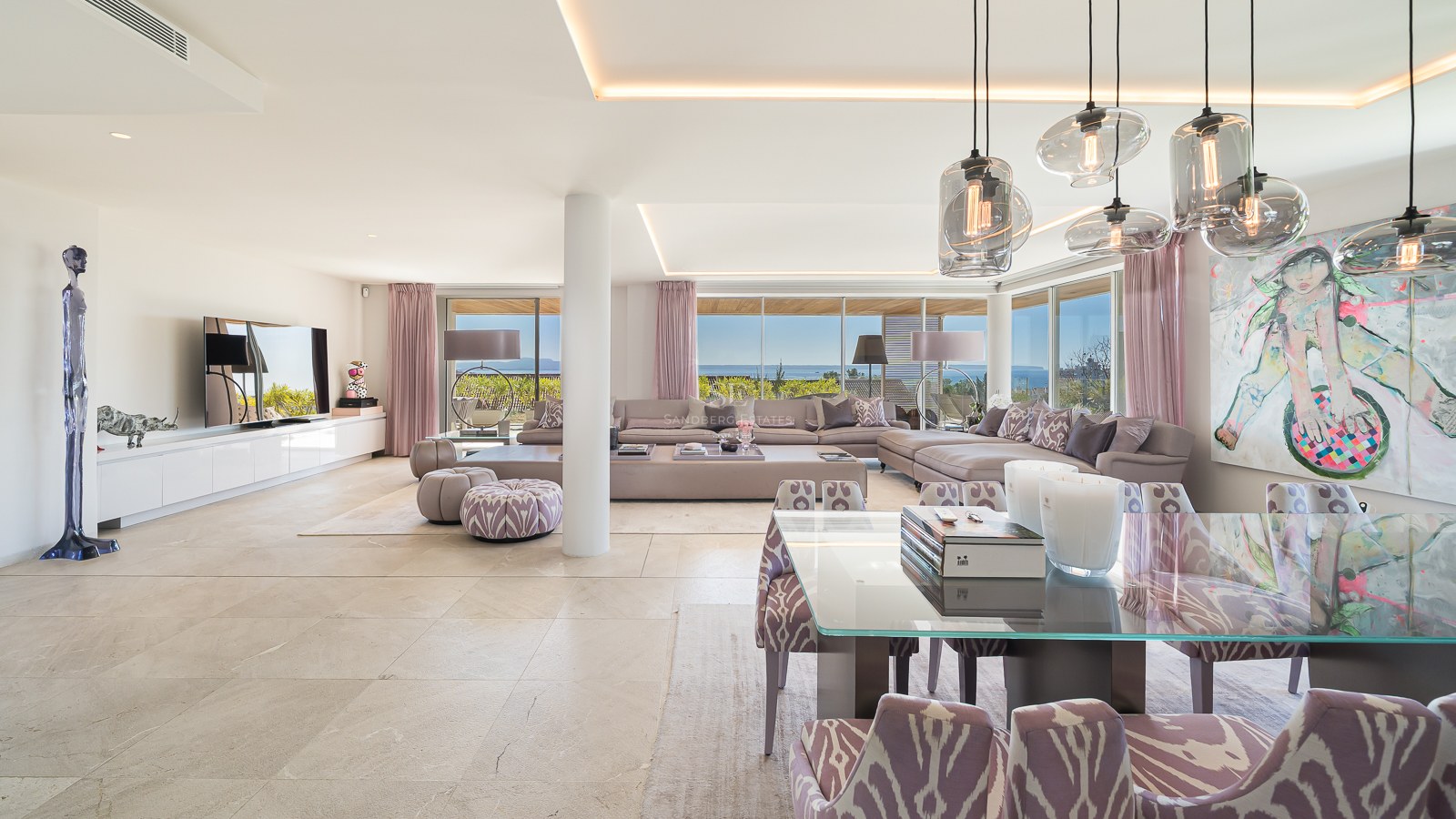 Bright open-plan living and dining room with marble floors and large windows overlooking the sea and coastline.