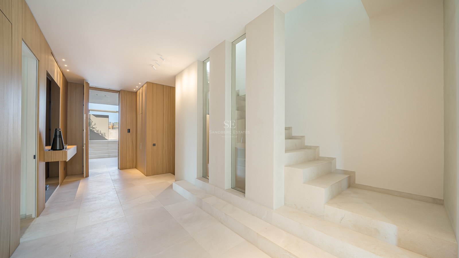 Couloir moderne avec sols en pierre crème, escalier en pierre minimaliste et boiseries en chêne clair.