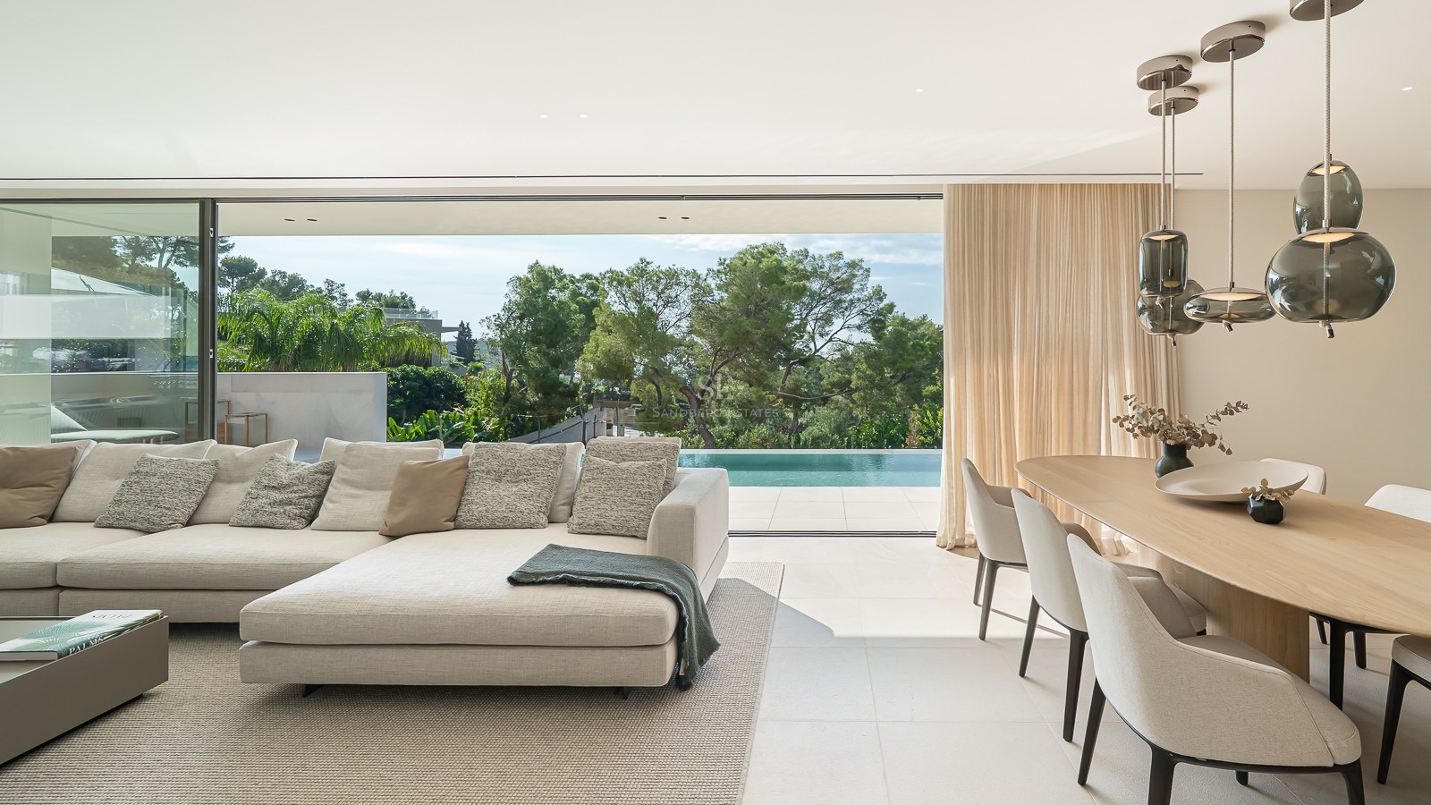 Salon moderne élégant avec canapé beige, coin repas et grandes baies vitrées ouvrant sur une terrasse avec piscine.