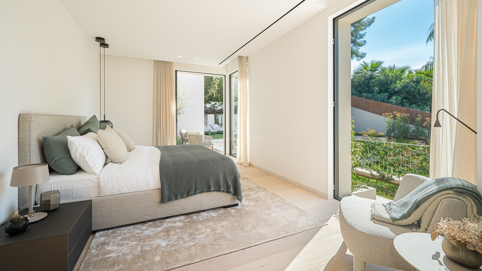 Chambre principale moderne avec grand lit, baies vitrées et vue sur un jardin luxuriant.
