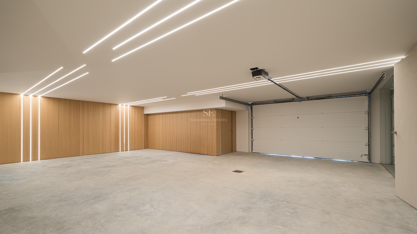 Vaste garage moderne avec sol en béton, panneaux muraux en bois et bandes lumineuses LED au plafond.