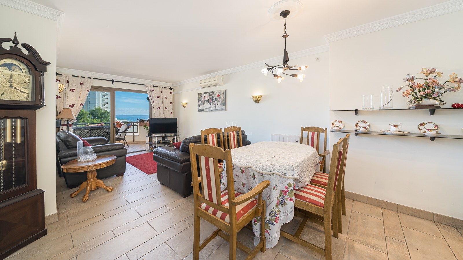 Open plan living and dining room featuring a grandfather clock, leather sofas, and a balcony overlooking the Mediterranean Sea.