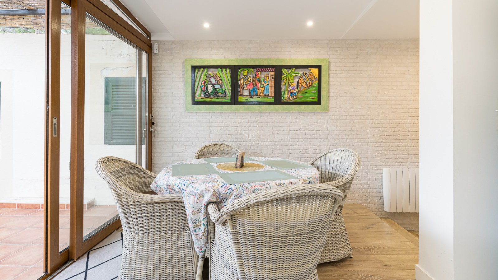 Dining area featuring wicker chairs, a white brick wall, and sliding glass doors.