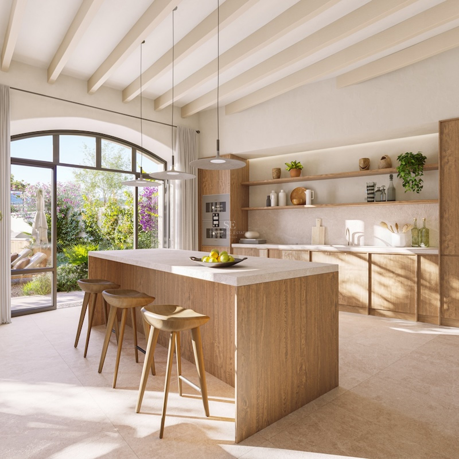 Bright kitchen featuring a large wooden island, designer stools, and arched doors opening to a sunny garden.