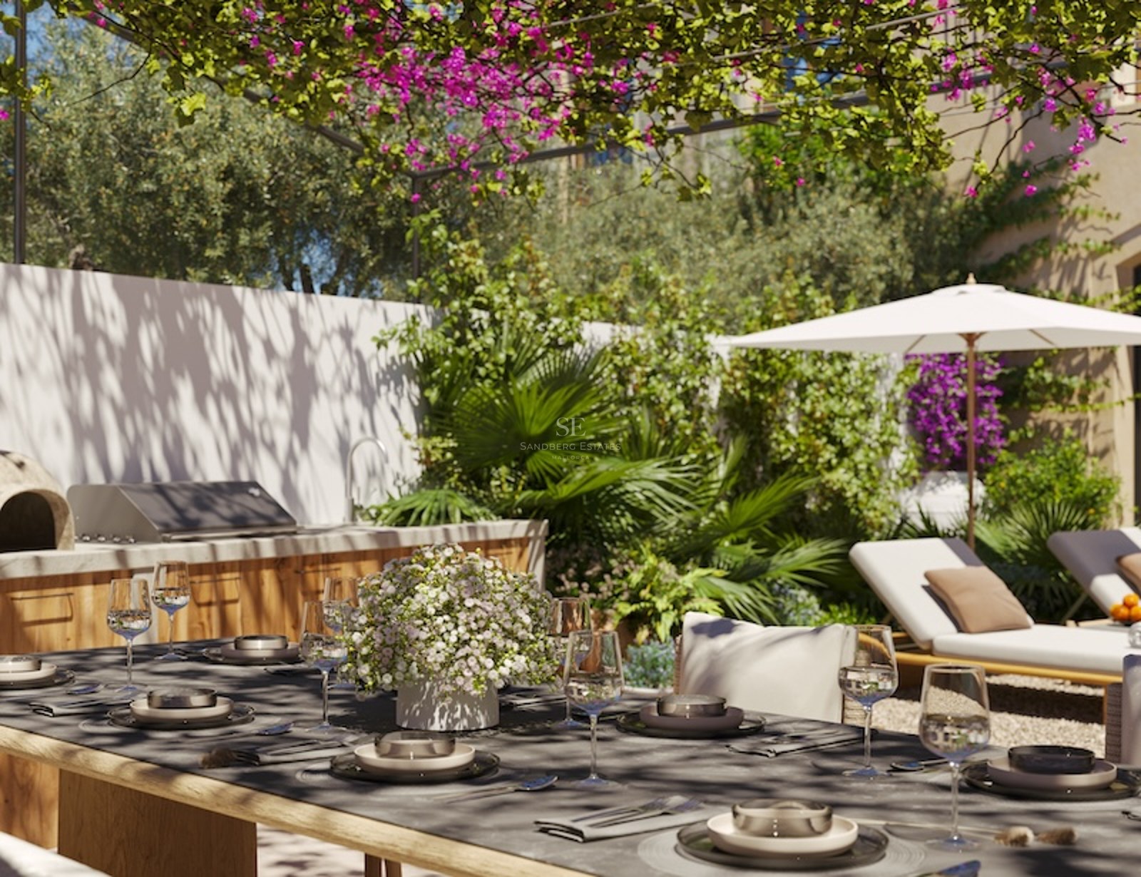 Sun-drenched terrace featuring an outdoor kitchen, dining under a flowered pergola, and loungers with an umbrella.