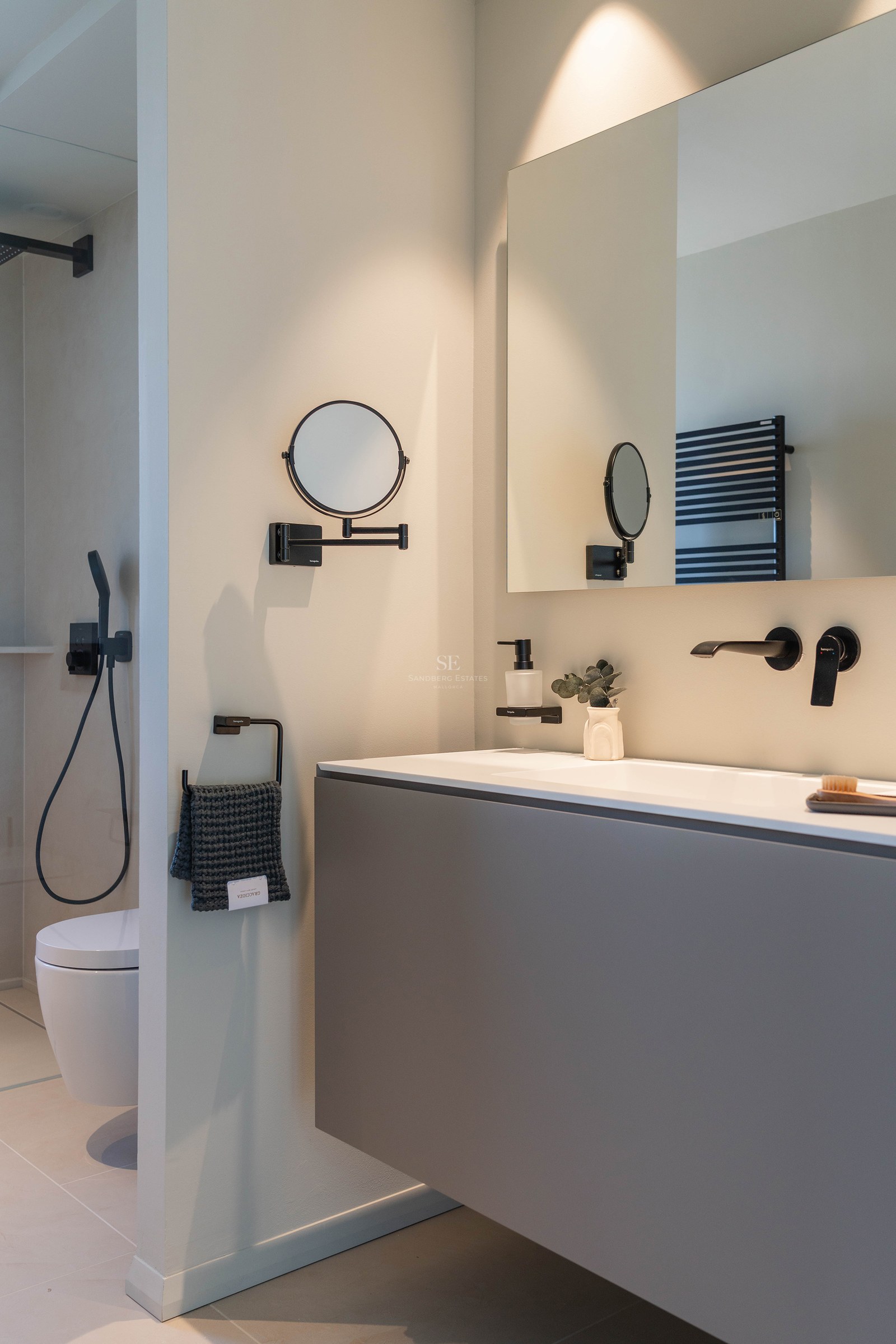 Modern bathroom featuring a grey floating vanity, matte black fixtures, and a large rectangular mirror.