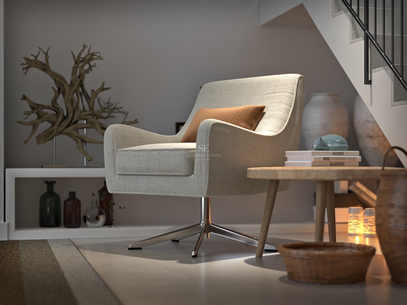 A beige swivel armchair in a minimalist interior nook under stairs with a wood table and decorative art pieces.