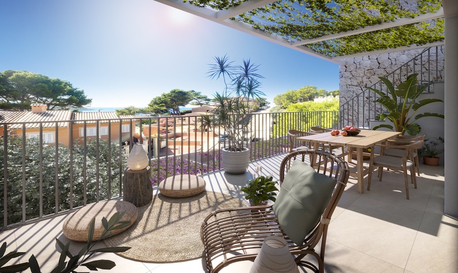 Terraza soleada con mesa de comedor de madera, silla de ratán y pérgola con plantas frente al mar.