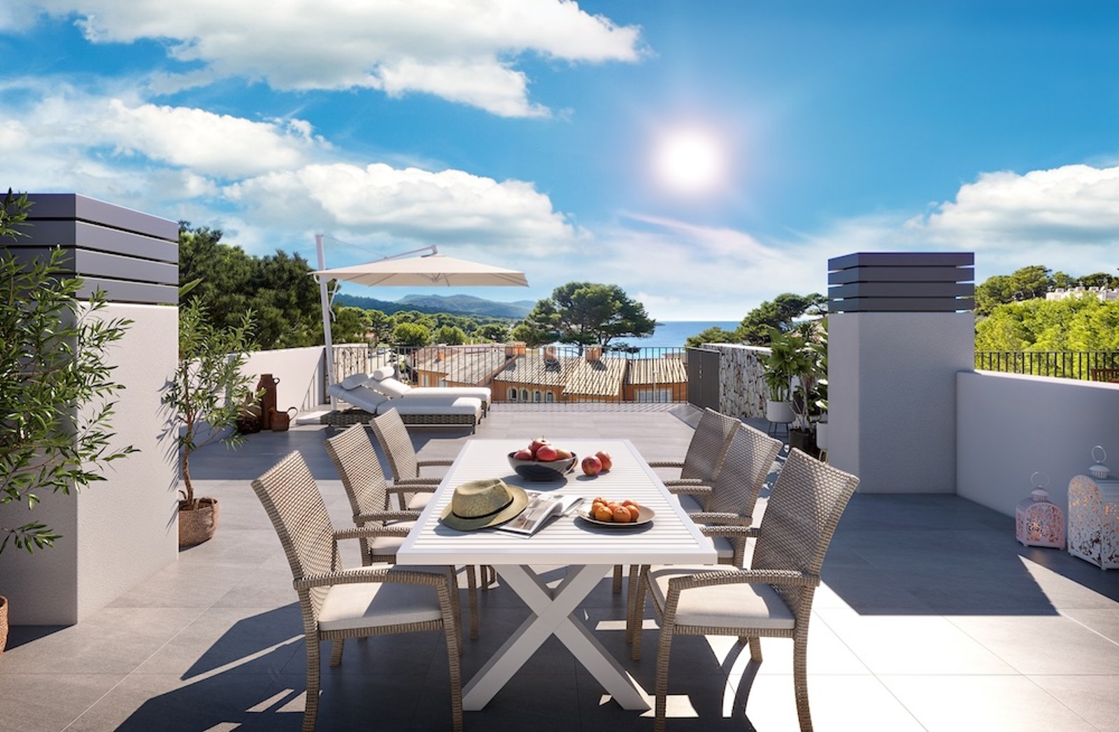Terraza soleada con comedor exterior, tumbonas y vistas panorámicas al mar y las colinas costeras.