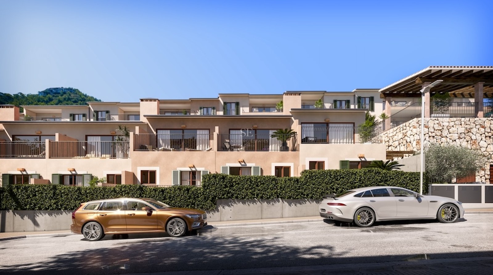 Modern apartment building with balconies, stone walls, and luxury cars parked on the street under a clear blue sky.