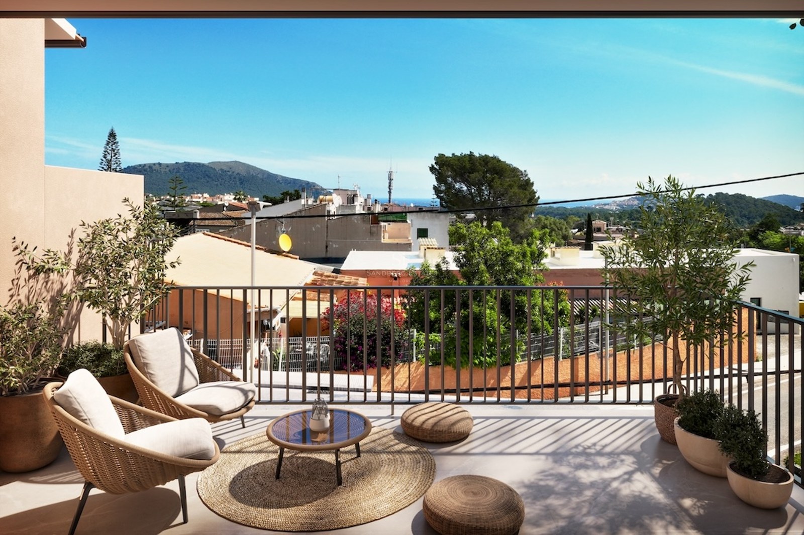 Terraza soleada con sillones de mimbre, olivos y vistas a un pueblo mediterráneo y montañas.