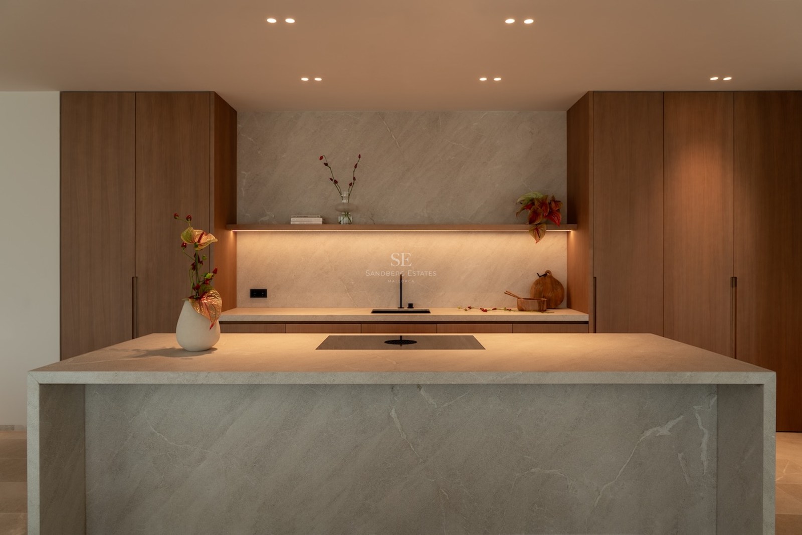 Modern kitchen featuring a large stone waterfall island, warm wood cabinetry, and integrated LED ambient lighting.