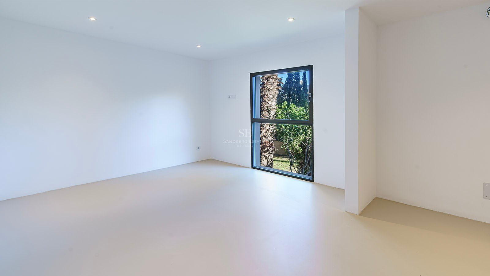 Habitación minimalista vacía con paredes blancas, suelo claro y ventana vertical con vistas a una palmera.