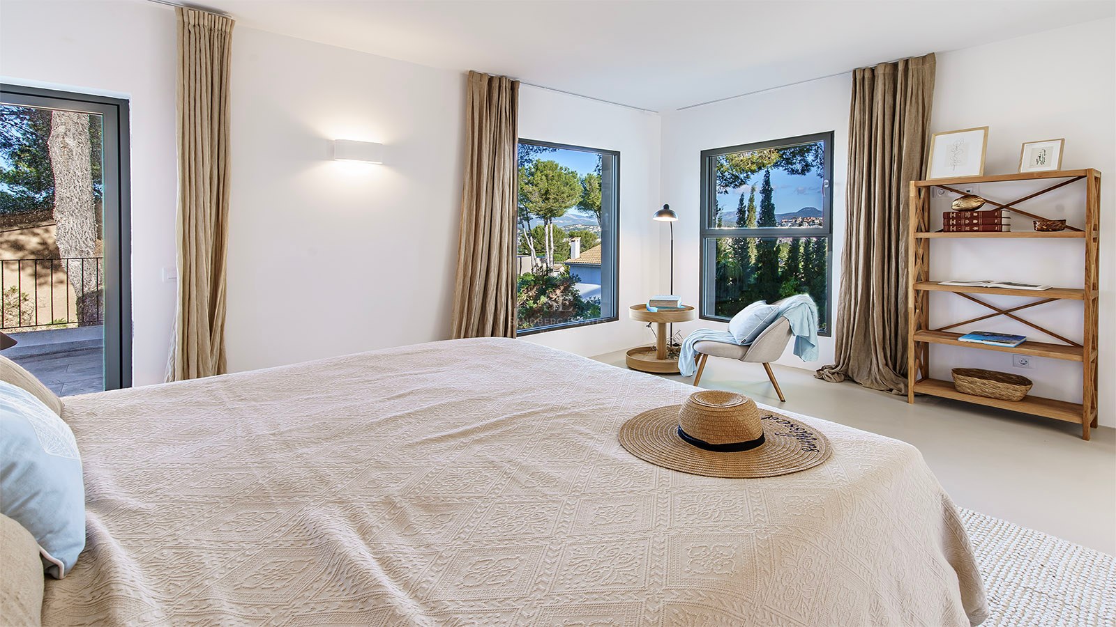 Dormitorio moderno con paredes blancas, cortinas de lino, muebles de madera y vistas a un paisaje verde.