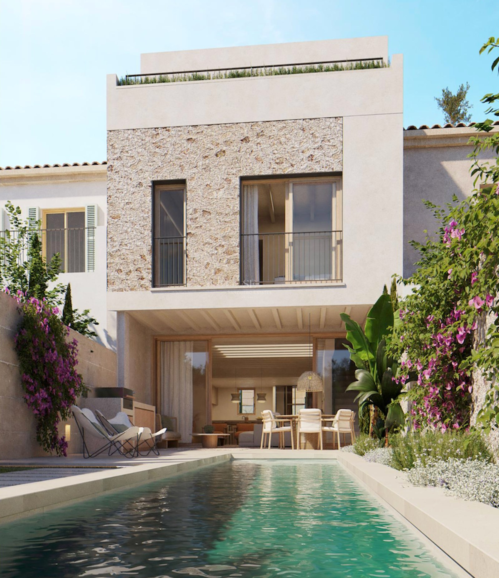 A lap pool in front of a modern white villa with natural stone cladding and vibrant bougainvillea flowers.