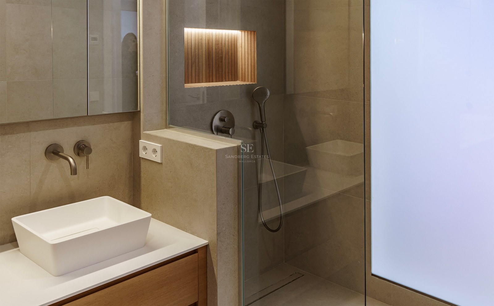 Modern bathroom featuring a white vessel sink, stone-tiled walls, and a glass walk-in shower with an illuminated wood niche.