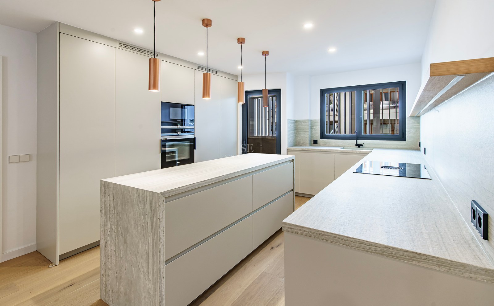 Contemporary white kitchen featuring a stone island, copper pendant lights, and wood flooring.
