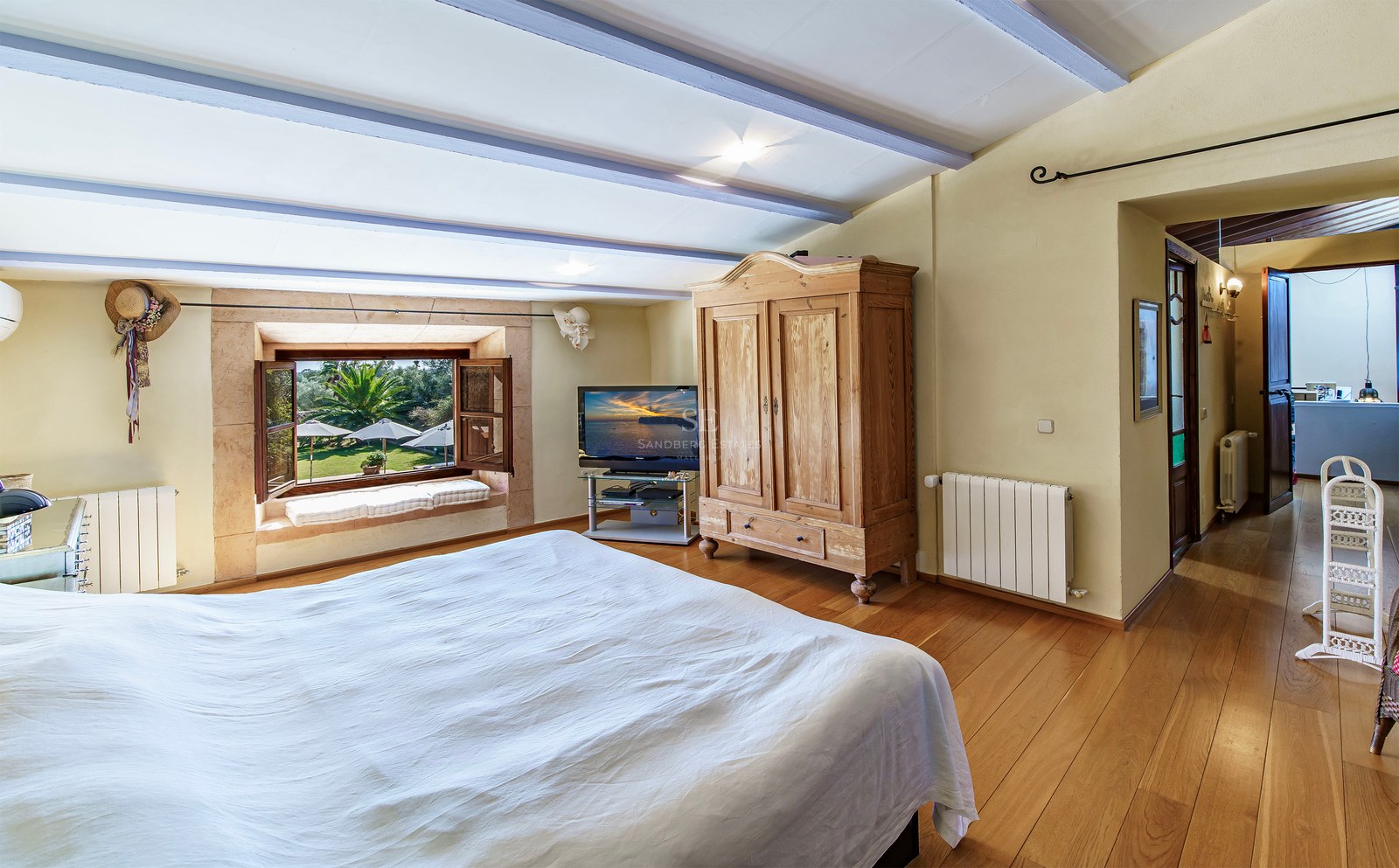 Gemütliches Schlafzimmer mit Holzböden, rustikalem Schrank und Fenster mit Blick auf einen üppigen Garten.