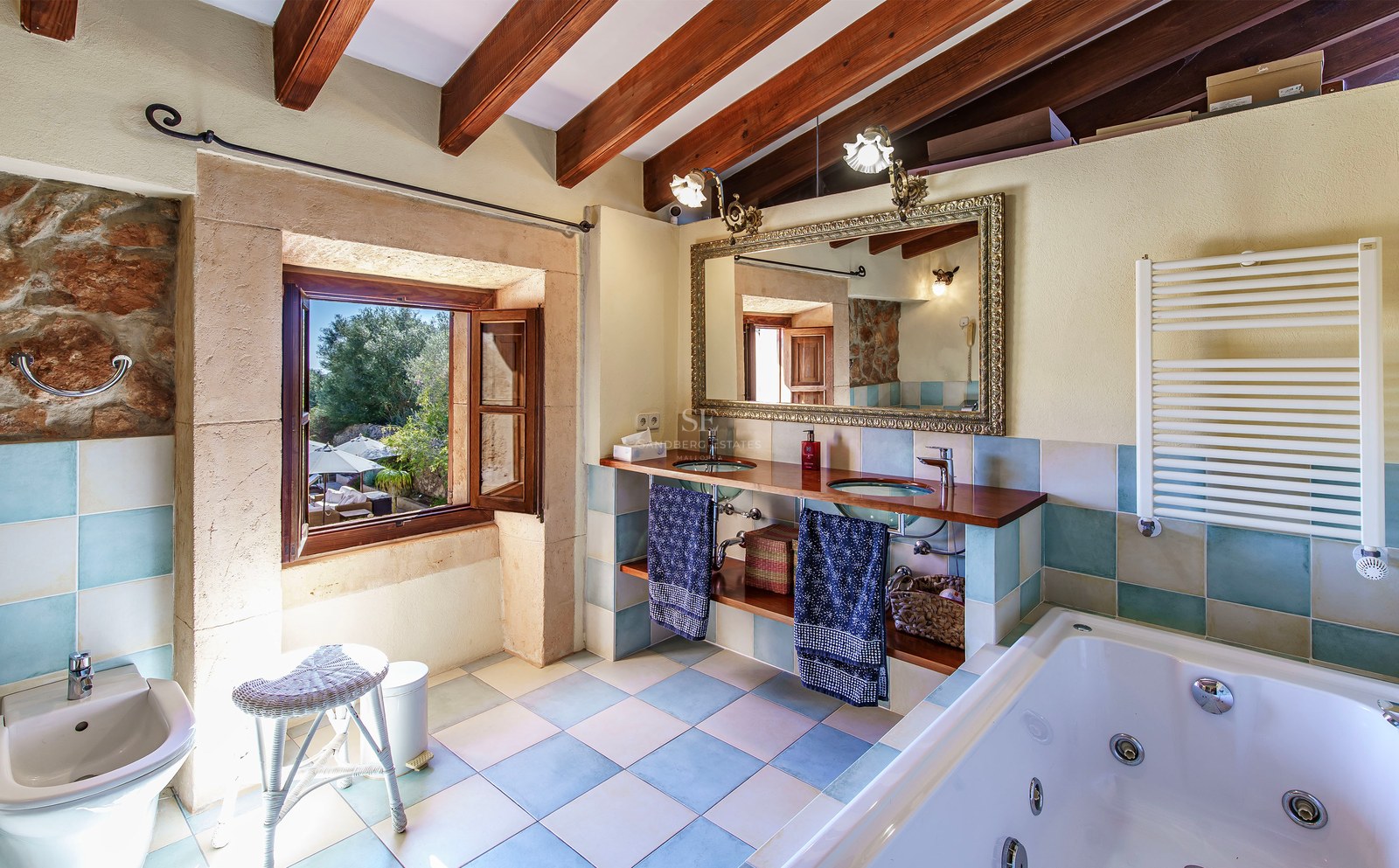 Hauptbadezimmer mit Holzbalken, Doppelwaschbecken aus Glas, Prunkspiegel und Whirlpool-Badewanne.