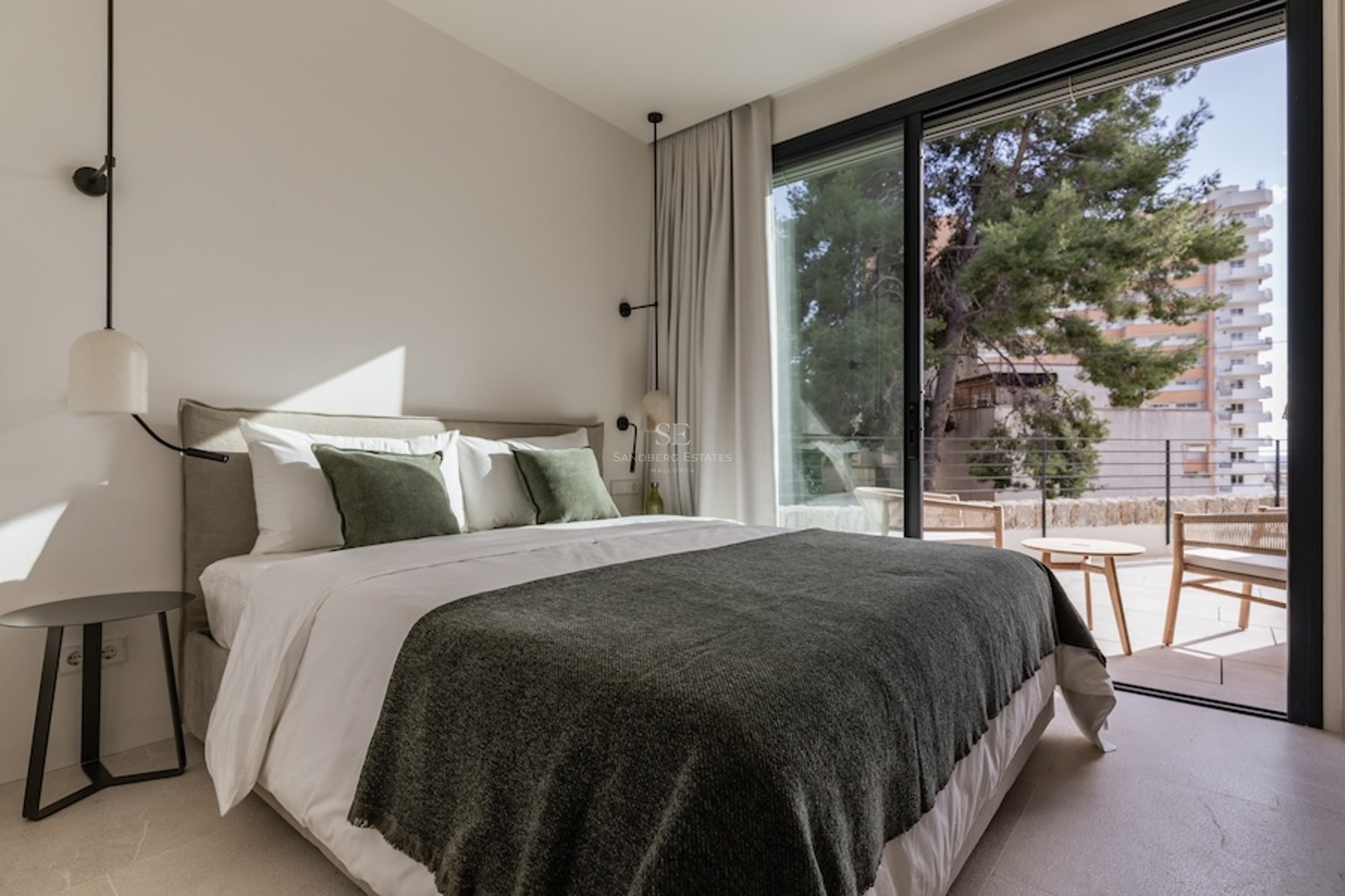 Bright bedroom featuring a double bed with green accents and large glass sliding doors opening to a terrace.