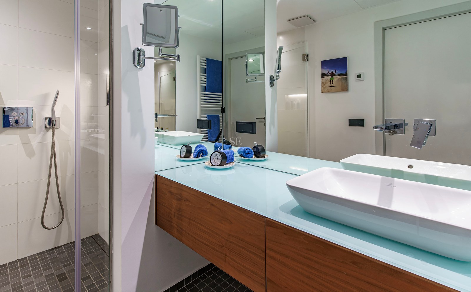 Modern bathroom featuring a white vessel sink on a floating wood vanity next to a walk-in shower with mosaic floor.