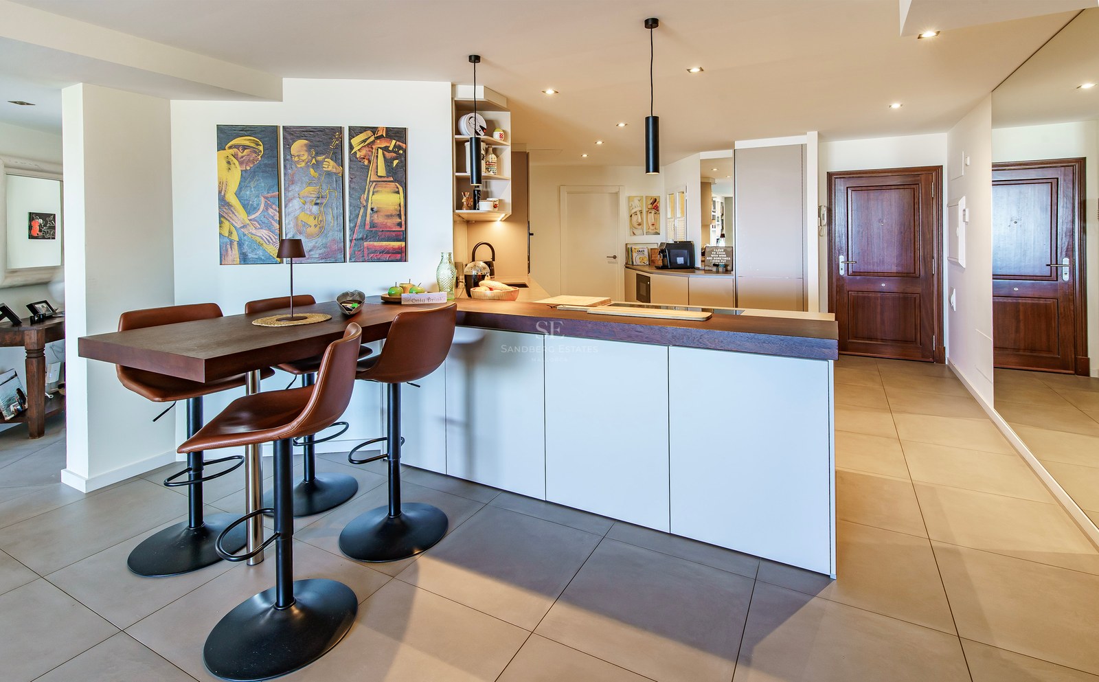 Modern white kitchen island featuring a dark wood breakfast bar and leather stools against a minimalist backdrop.