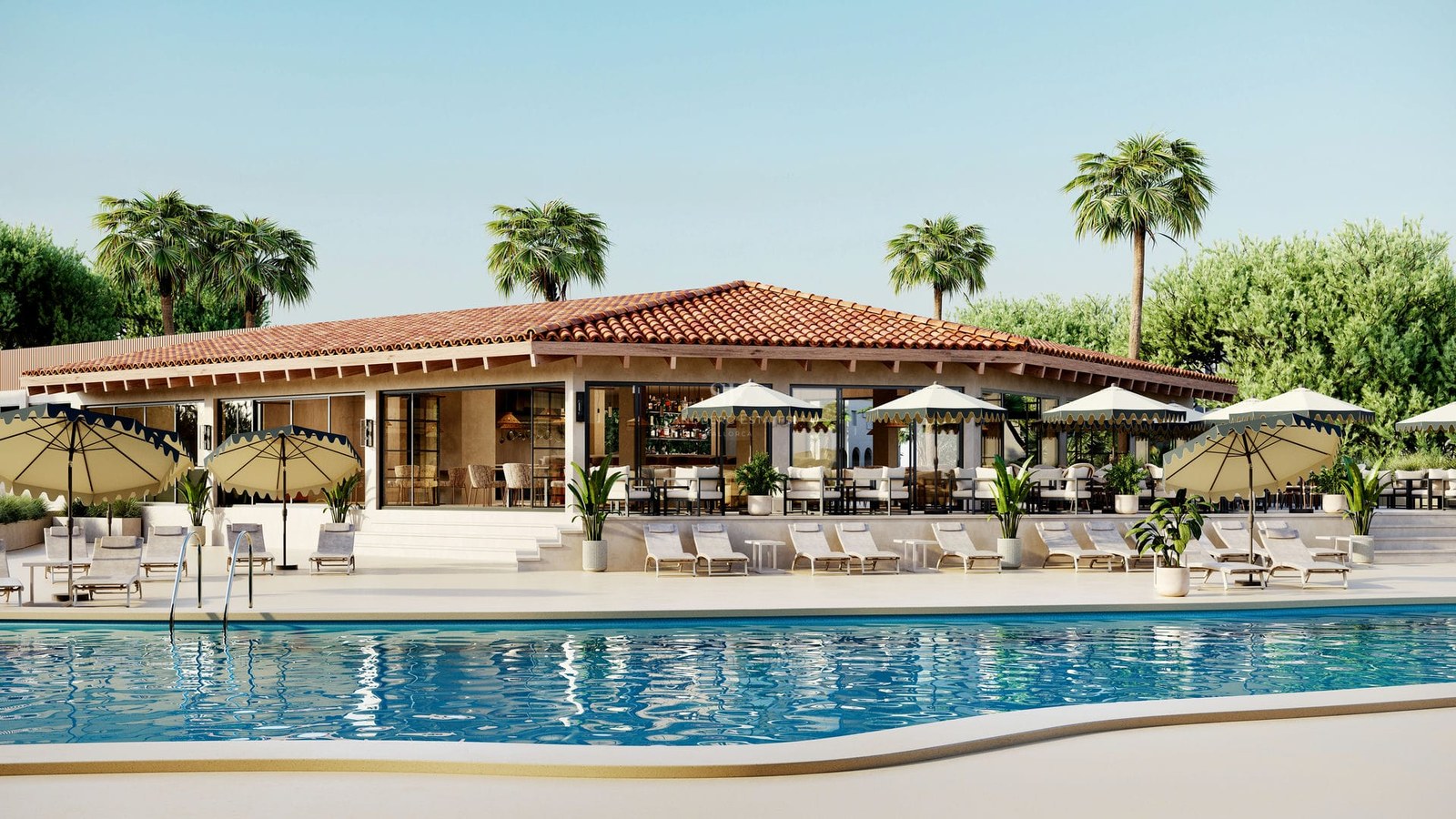 Large blue swimming pool in front of a terracotta-roofed building with sun loungers and umbrellas under a clear sky.