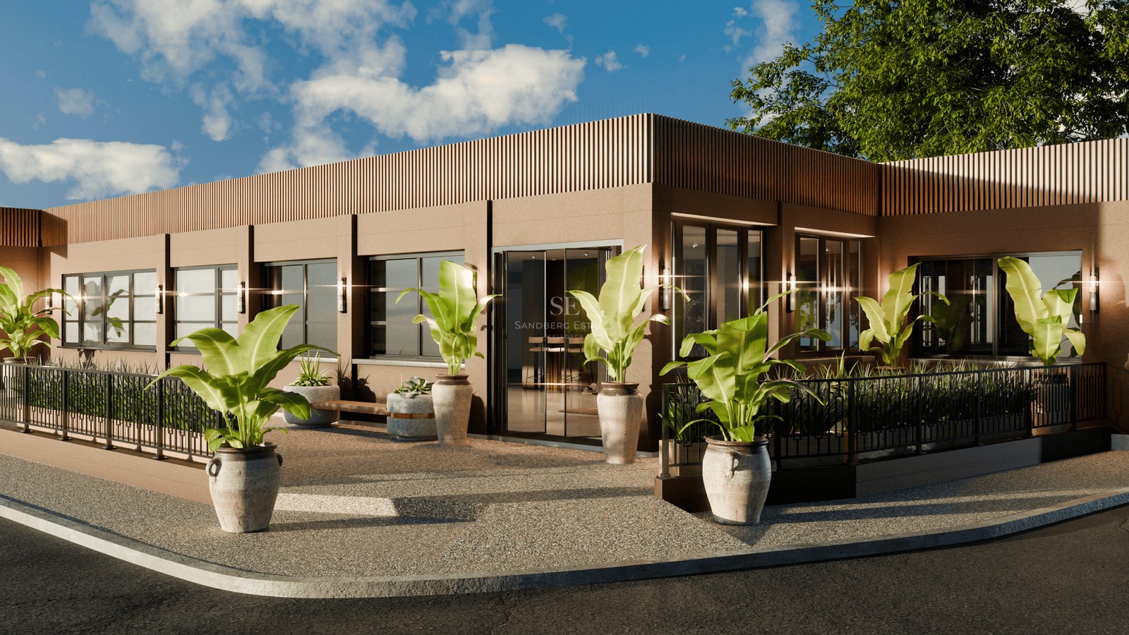 Exterior view of a modern brown building with large glass windows and potted tropical plants under a blue sky.