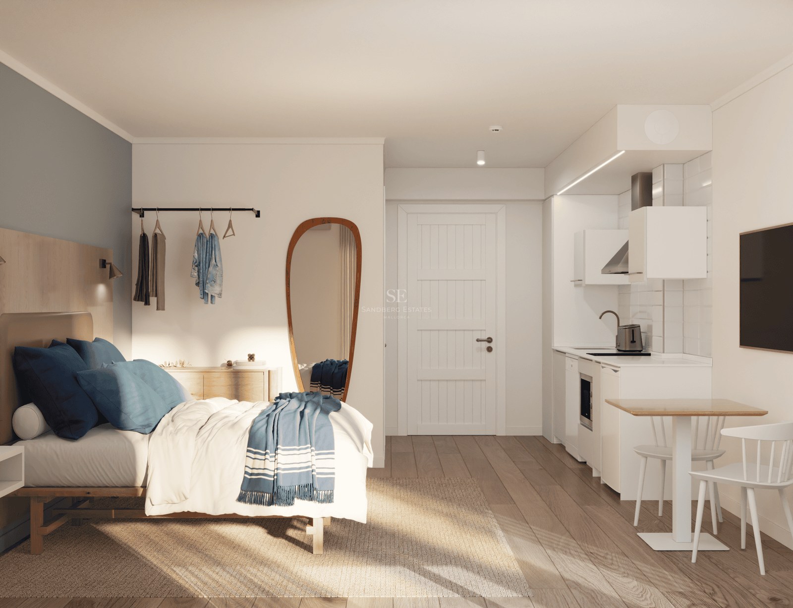 Studio moderne avec lit, kitchenette blanche, petite table et lumière naturelle sur parquet clair.