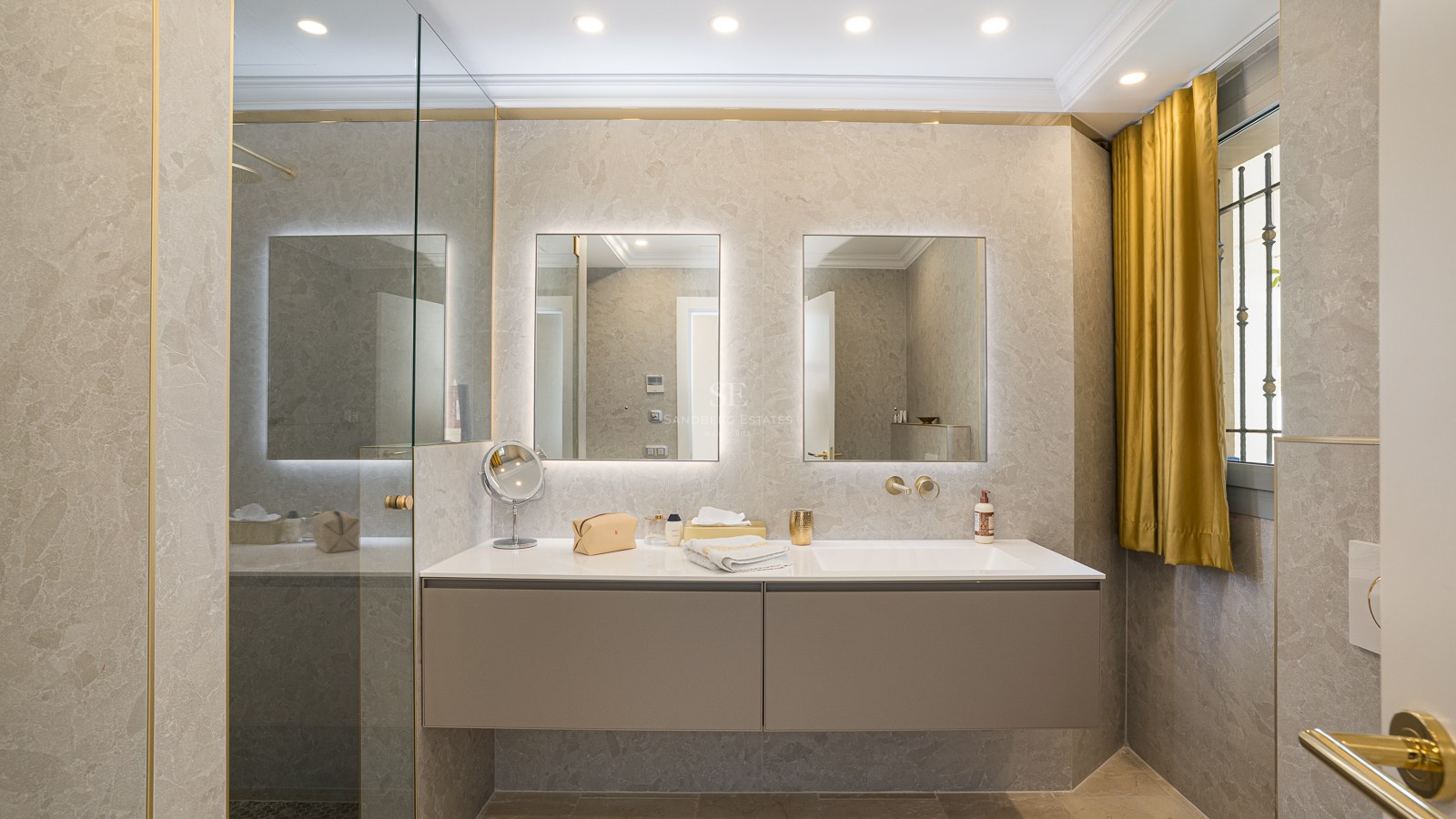 Salle de bains contemporaine avec double vasque suspendue taupe, miroirs rétroéclairés et murs en pierre naturelle.