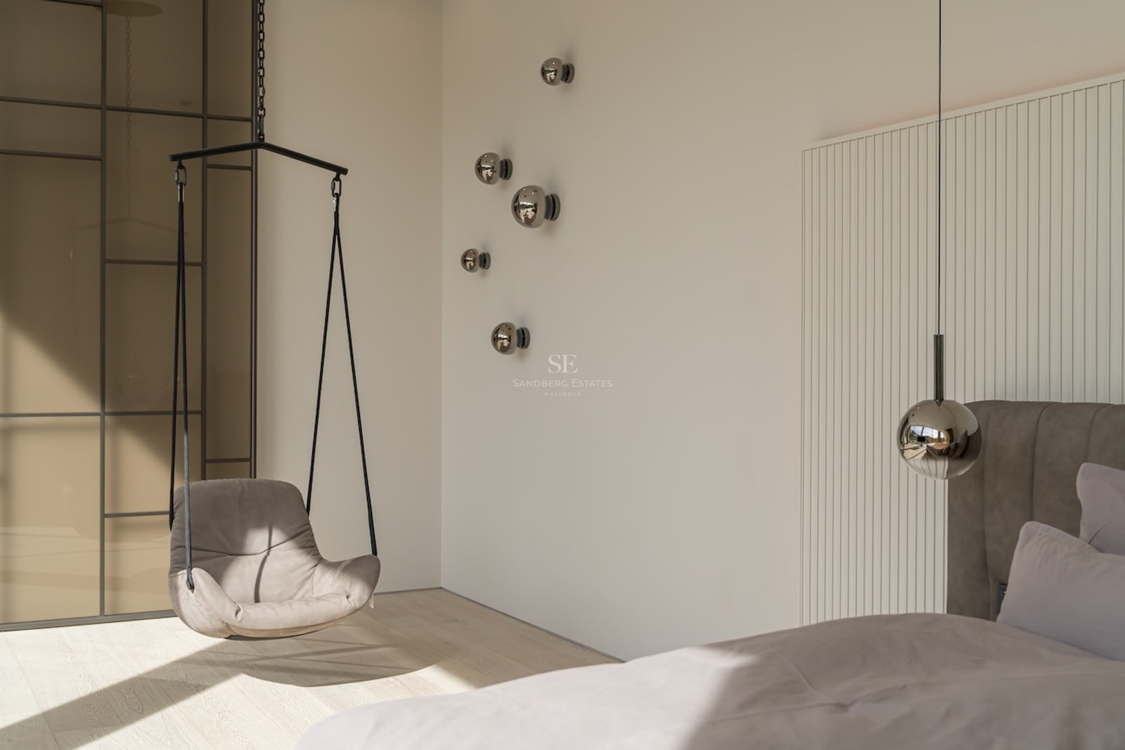Coin de chambre moderne avec fauteuil suspendu gris, appliques murales sphériques et boiseries cannelées blanches.