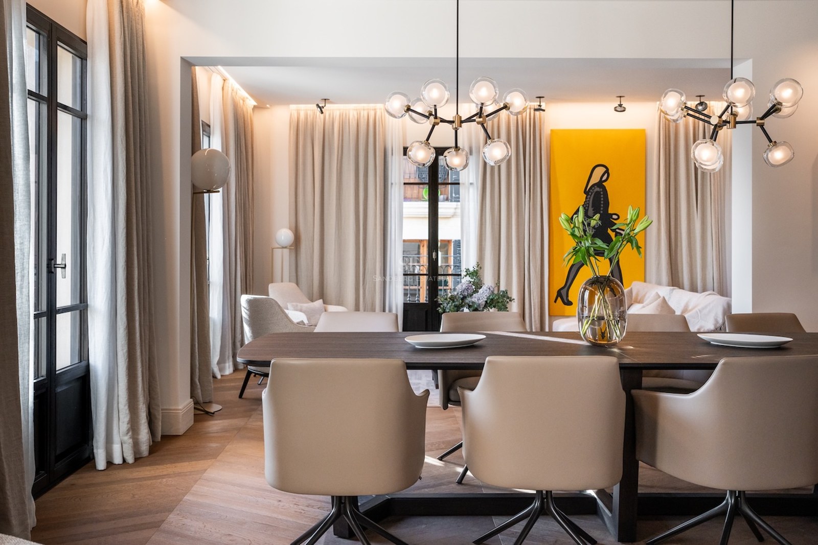 Comedor moderno con mesa de madera oscura, sillas de cuero beige y lámparas de cristal de diseño.
