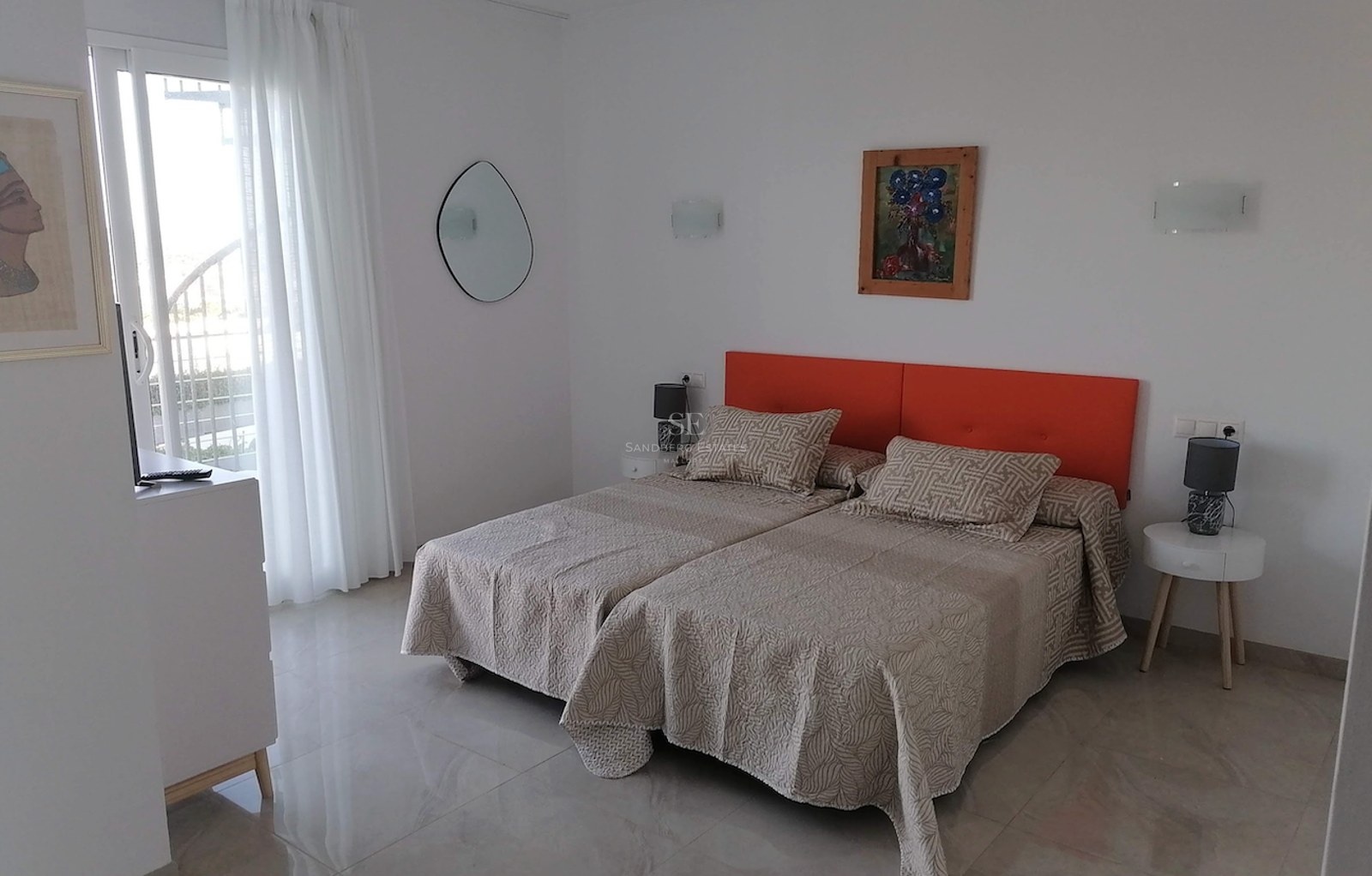 Bedroom featuring twin beds with an orange headboard, polished stone floors, and a glass door leading to a terrace.