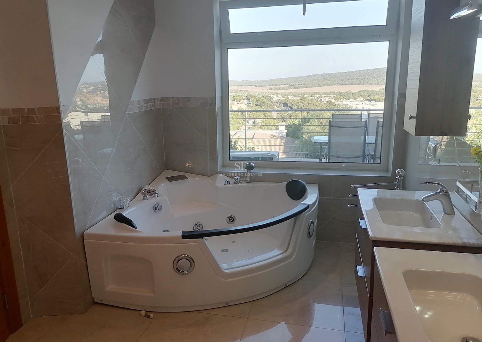 Contemporary bathroom featuring a corner jacuzzi, double vanity, and a large window overlooking a scenic valley.