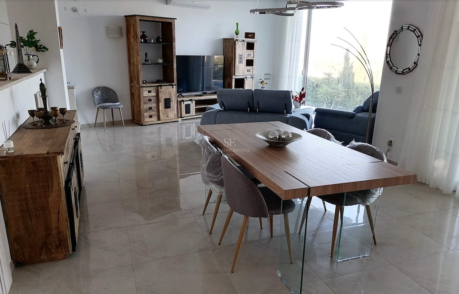 Spacious living and dining area featuring polished porcelain tiles, wooden cabinetry, and floor-to-ceiling windows.