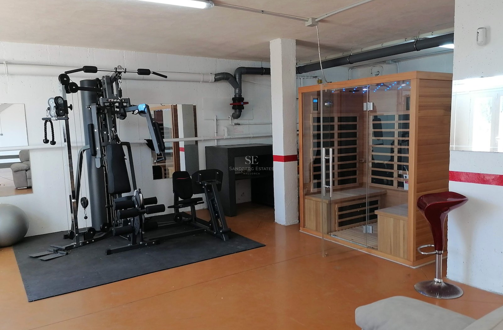 Indoor home gym featuring a multi-station weight machine and a private wooden sauna cabin.