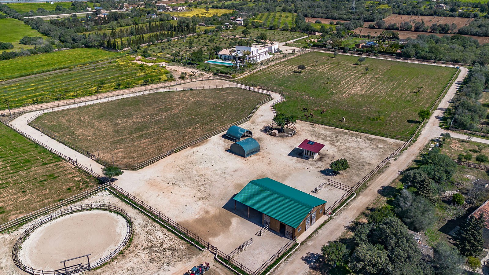 High-angle aerial view of a luxury Mediterranean estate featuring extensive equestrian facilities, stables, and a villa.