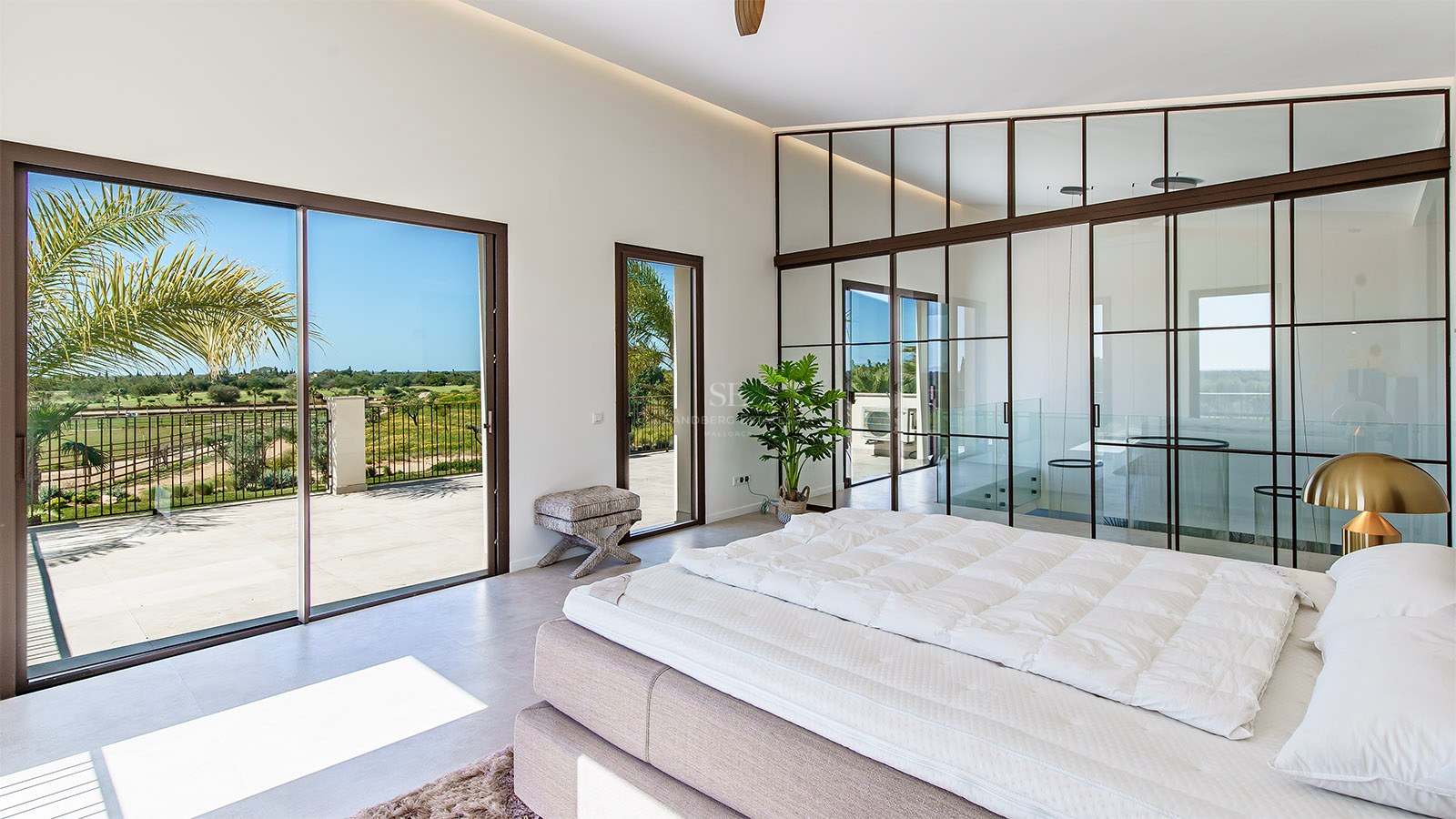 Modern bedroom featuring an industrial-style glass partition wall, black frames, and terrace access with scenic views.